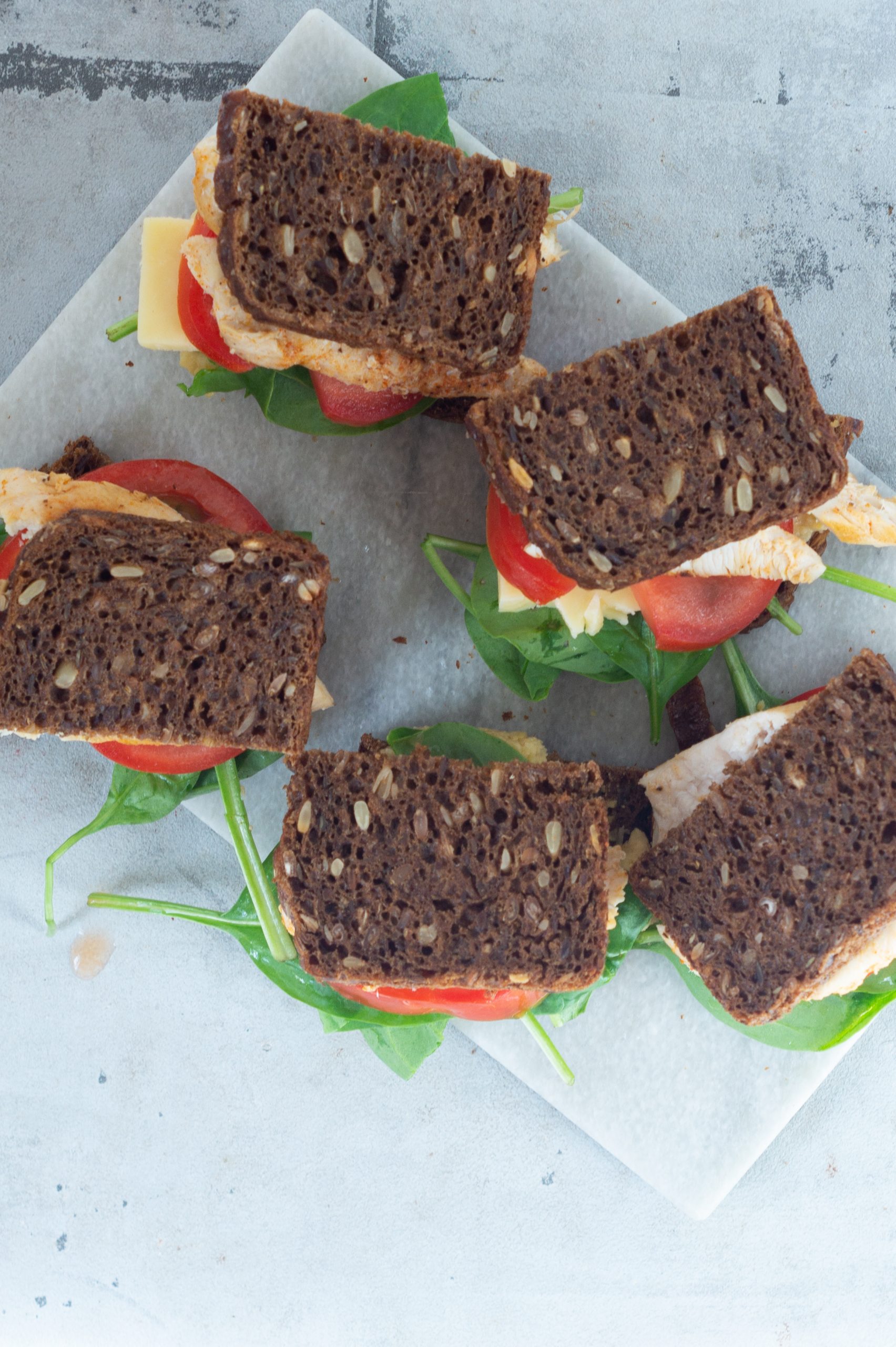 Rugbrødssandwich med hummus, kylling, ost, spinat og tomat